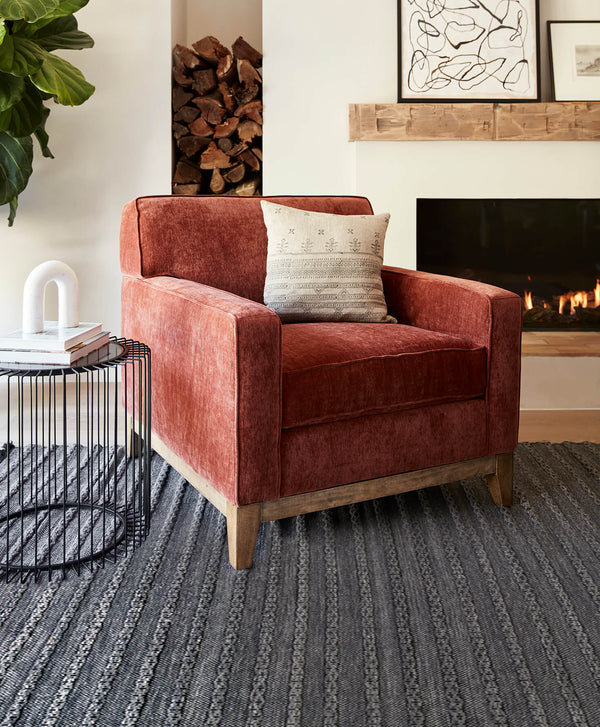 Modern Red Lounge Chair with a Wooden Base on a Blue Striped Rug with a Fireplace