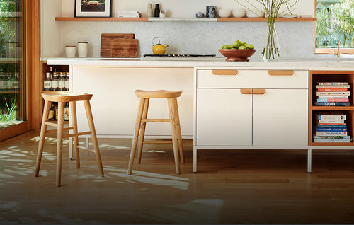 Kitchen with brown wood floors, white cabinets and two brown wooden counter stools