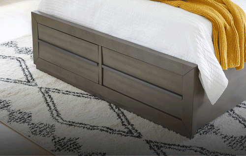 Grey bed with white bedding on a beige rug with storage footboard drawers extending in and out
